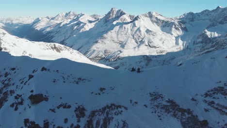 Luftaufnahme-über-Freeride-Skifahrer,-Die-Sich-Vom-Berggipfel-Zum-Freestyle-Bereit-Machen---Rückwärts,-Drohnenaufnahme