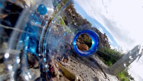 Discarded-plastic-bottles-litter-the-ground-and-roll-in-the-wind---trash-polluting-the-environment-as-seen-from-inside-a-water-bottle