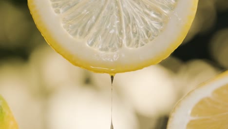 Extreme-close-up-water-drop-pouring-on-half-slice-cut-of-fresh-lemon-in-slow-motion,-Blurred-background