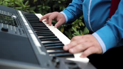 Mittlere-Aufnahme-Eines-Mannes-Mit-Blauem-Hemd,-Der-Im-Garten-Auf-Einer-Synthesizer-Tastatur-Spielt