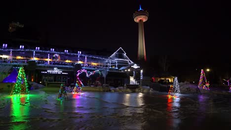 Niagara-Falls-Queen-Victoria-Place-with-Skylon-Tower-in-distance-night-with-frozen-ice-and-snow-during-winter-festival-of-lights-Christmas-trees-reflecting-on-ice-during-winter-close-up