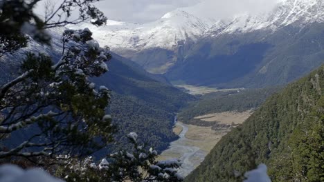 Snowy-mountains-lookout-over-a-beautiful-green-valley-with-a-river-running-through