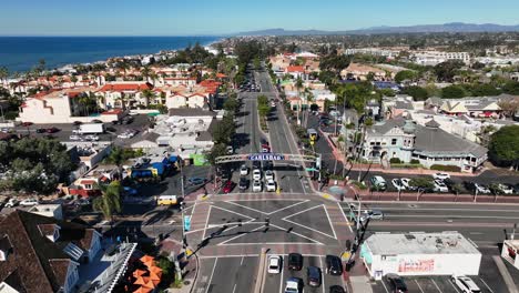 Drone-rotating-shot-over-the-main-crossing-in-Carlsbad,-California,-USA-on-a-bright-sunny-day-with-the-view-of-the-blue-ocean-in-the-background
