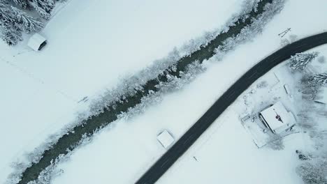Aerial-shot-of-a-snow-covered-mountain-town,-winding-road-through-the-valley