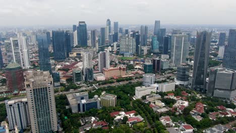 Skyline-of-the-SCBD-area-in-cloudy-Jakarta,-Indonesia,-forward-aerial