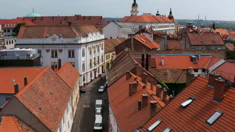 Vehicles-Parked-In-The-Roadside-Of-Streets-Between-Red-Roofed-Buildings-In-Pecs,-Hungary