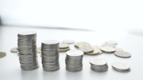 Nahaufnahme-Von-Geld-Sparen-Hand,-Die-Münzen-Auf-Stapel-Auf-Tisch-Mit-Weißem-Hintergrund-Legt