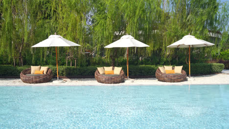 umbrella-with-bed-pool-around-swimming-pool-with-ocean-sea-background---holiday-and-vacation-concept