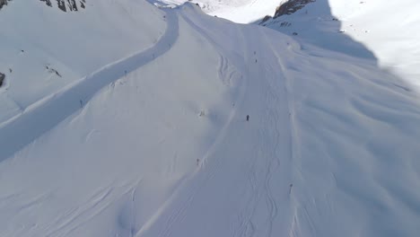 Aerial-drone-view-following-downhill-skiing-on-the-slopes-of-the-sunny-Alps