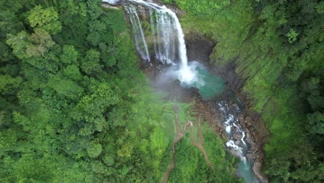 Aerial-rising-of-Eco-Chontales-waterfall-falling-into-rocky-natural-pond-surrounded-by-dense-green-rain-forest,-Costa-Rica
