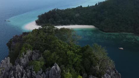 Wunderschöne-Graue-Felsen-Mit-Bäumen-Bedeckt,-Während-Im-Hintergrund-Traditionelle-Thailändische-Boote-Am-Weißen-Sandstrand-Von-Ko-Poda-Und-Seinem-Wunderschönen-Klaren-Meer-Festgemacht-Sind