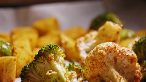 A-close-up-macro-view-of-fresh-broccoli-and-cauliflower-covered-in-seasoning-on-a-baking-tray,-the-vegetables-cooling-after-roasting-in-an-oven-and-part-of-a-healthy-balanced-meal