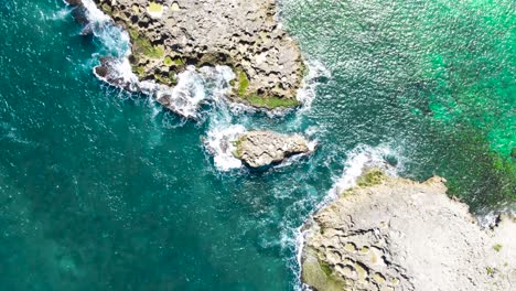 Puerto-Rico-green-and-blue-water-splashing-against-rocky-island-from-above-drone-shot