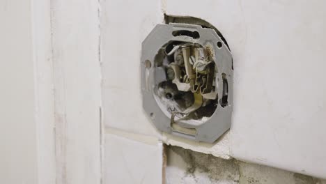 A-close-up-shot-of-an-electrical-socket-that-has-recently-been-installed-into-a-tile-on-a-bathroom-wall,-the-bathroom-currently-undergoing-refurbishment-with-repairs-and-maintenance-being-done