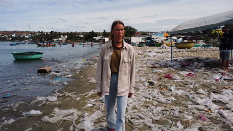 Junge-Kaukasische-Frau,-Die-Umweltfreundliche-Nachhaltige-Kleidung-Trägt-Und-Barfußsandalen-Am-Tropischen-Strand-Mit-Müllverschmutzung-Durch-Plastikabfälle-Spazieren-Geht