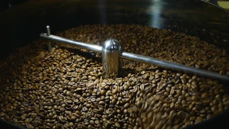 Coffee-beans-being-stirred-on-cooling-plate-after-being-roasted-medium-shot