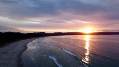 Colorful-Sunset-Over-Water-Surface-In-Spirits-Bay,-New-Zealand---aerial-drone-shot