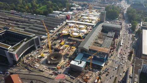 Aerial-flying-above-huge-railroads,-intersection-and-construction-site-of-main-train-station-Stuttgart-S21-with-cranes-and-construction-worker-in-Stuttgart,-Germany