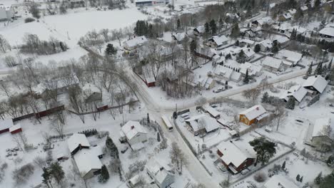 Downward-looking-aerial-view-tracking-a-bus-driving-on-snow-covered-roads-in-residential-area-of-Pitkämäki-during-winter-daytime