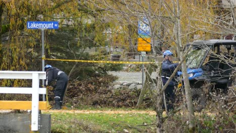 Police-officers-securing-perimeter-with-yellow-tape,-handheld-shot