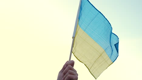 Hand-waving-Ukrainian-flag-at-a-protest,-Prague,-close-up-slow-motion