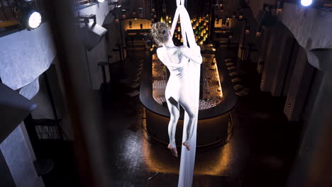 Female-aerialist-doing-the-iron-cross-pose-on-silks-in-a-music-club