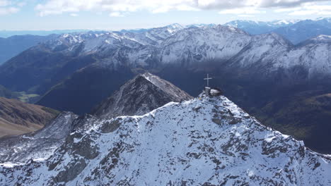 Luftbogenaufnahme-Eines-Kreuzes-Auf-Dem-Gipfel-Des-Otzi-Gipfels-Des-Eismannes,-Einem-Atemberaubenden-Aussichtspunkt,-Umgeben-Von-Den-Malerischen-Schneebedeckten-Bergen-Des-Schnalstaler-Gletschers,-Tirol,-Italien