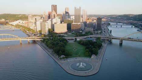 Aerial-view-of-the-Point-state-park-fountain-and-the-sunlit-Pittsburgh-skyline---tilt,-drone-shot