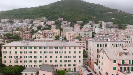 Apartment-buildings-of-Genoa-with-mountains-in-background,-aerial-side-flying-view