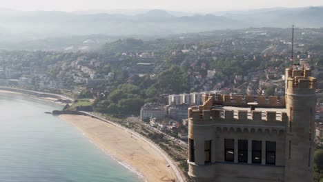 Majestic-medieval-tower-and-skyline-of-San-Sebastian-city,-cinematic-aerial-view