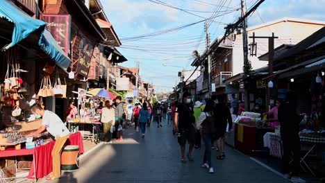 Vendedores-Que-Exhiben-Sus-Productos-A-Lo-Largo-De-La-Calle-Peatonal-En-Chiang-Khan,-Loei,-Mientras-Los-Turistas-Buscan-Algo-Para-Comprar-Y-Comer,-Tailandia