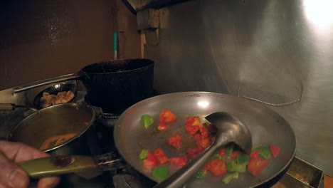 Hands-of-check-pouring-oil-into-pan-of-vegetables-and-curry-tofu-with-flames-bursting-upward-during-stirring
