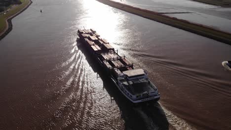 Aerial-Circle-Dolly-über-Missouri-Frachtschiff-Entlang-Des-Flusses-Noord-Gegen-Strahlenden-Sonnenschein,-Der-Sich-Auf-Dem-Wasser-Widerspiegelt
