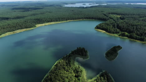 Shadows-of-clouds-swimming-over-majestic-lake-landscape-of-Lithuania,-aerial-drone-view