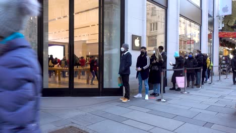 Weite-Sicht-Auf-Menschen-Mit-Gesichtsmasken,-Die-Sich-Vor-Dem-Apple-Store-In-Wien-Anstellen