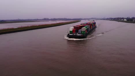 Antenne-über-Dem-Fluss-Noord-Mit-Blick-Auf-Das-Fps-Rijn-Schiff-Mit-Containern,-Das-Sich-An-Bewölkten-Tagen-Nähert