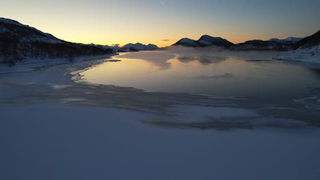 Moody-sunset-low-fly-over-frozen-fjord-during-the-polar-night-season---Northern-Norway---Scandinavia---Jornfjorden
