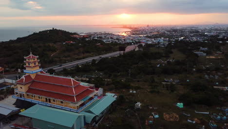 Buddhistischer-Schrein-Und-Panorama-Der-Stadt-Phan-Thiet,-Vietnam,-Luftaufnahme-Bei-Sonnenuntergang