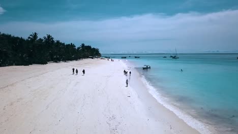 Great-aerial-flight-fly-backwards-drone-shot-over-white-sand-beach-turquoise-water-and-people-Paradise-dream-beach-Zanzibar,-Africa-Tanzania-2019-Cinematic-wild-nature-1080,-60p-by-Philipp-Marnitz