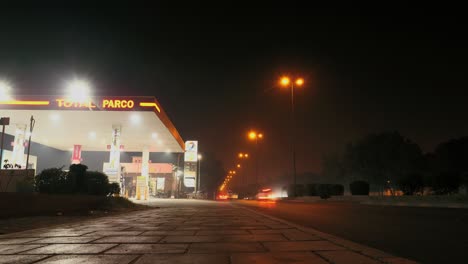 Night-Timelapse-Of-Traffic-Going-Past-Petrol-Station-Forecourt-In-Karachi