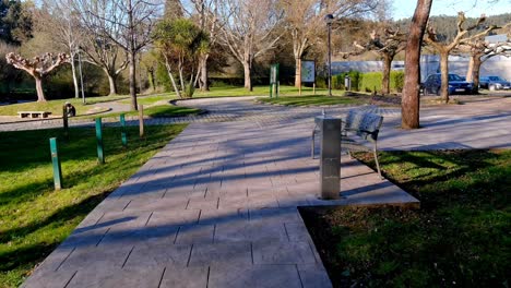 POV-Along-Empty-Sidewalks-At-Recreational-Park-Past-Bench