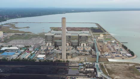 Industrial-aerial-shot-of-coastal-coalfield,-ultra-supercritical-coal-fired-power-plant-with-smokes-raising-from-chimney-located-at-lekir-bulk-terminal-jalan,-teluk-rubiah,-manjung,-perak,-malaysia