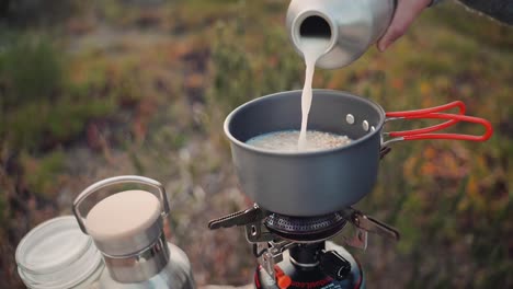 Slow-motion-footage-of-a-woman-pouring-milk-in-a-cooking-pot-while-camping-out-in-the-wild