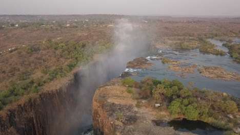 Aerial-orbits-Victoria-falls-revealing-whitewater-mist-in-gorge-below