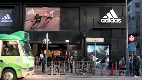 Fußgänger-Gehen-Am-Offiziellen-Store-Und-Logo-Der-Deutschen-Multinationalen-Sportbekleidungsmarke-Adidas-In-Hong-Kong-Vorbei