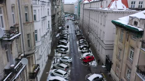 Aerial-view-over-a-narrow,-snowy-street-in-Warsaw,-cloudy,-winter-day-in-Poland