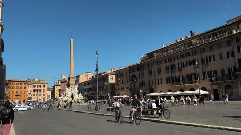 Toma-En-Cámara-Lenta-De-Personas-Caminando-Y-Ciclistas-Con-Bicicletas-En-Piazza-Navona-En-Roma-Durante-El-Verano