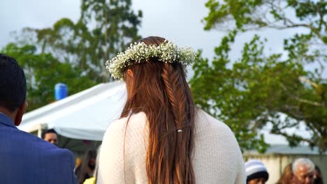 SAN-RAMON,-COSTA-RICA---MARCH-19,-2022:-the-bride,-shot-from-behind,-at-her-wedding-day,-wearing-a-flower-garland,-together-with-the-guests