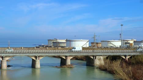 Verkehr-Auf-Der-Brücke-Vor-Einer-Kraftstoffraffinerie-In-Meeresnähe,-Echtzeitaufnahme,-Verschmutzungskonzept