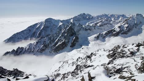 Panoramic-view-of-foggy-valley-between-High-Tatras-mountain-snow-capped-jagged-peaks,-Slovakia